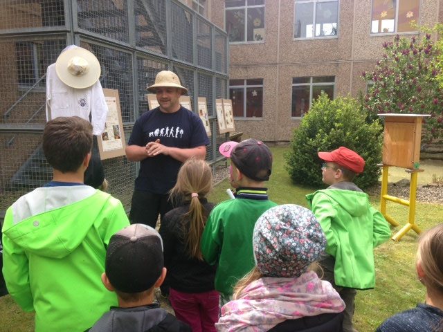 Ein Imker erklärt den Hortkindern seine Bienen